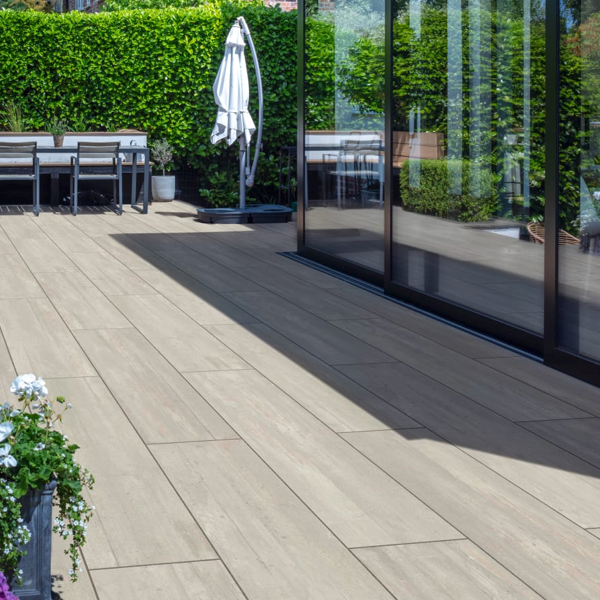 Wood-effect porcelain plank paving installed on a modern garden patio beside a glass extension. 