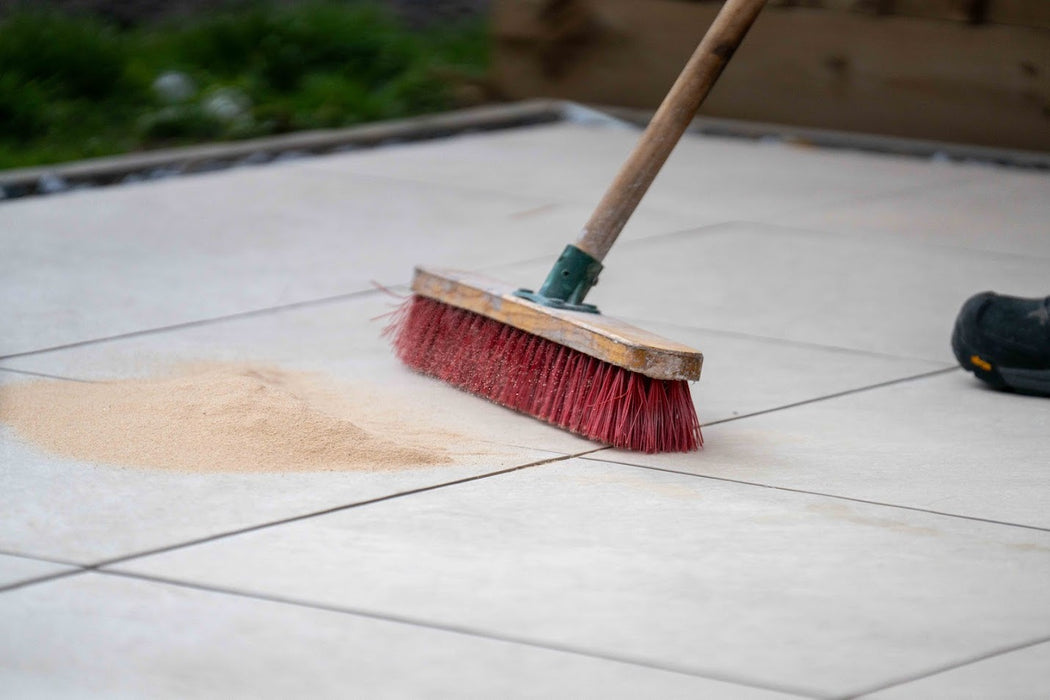 Red broom cleaning a tiled floor with a blurred background