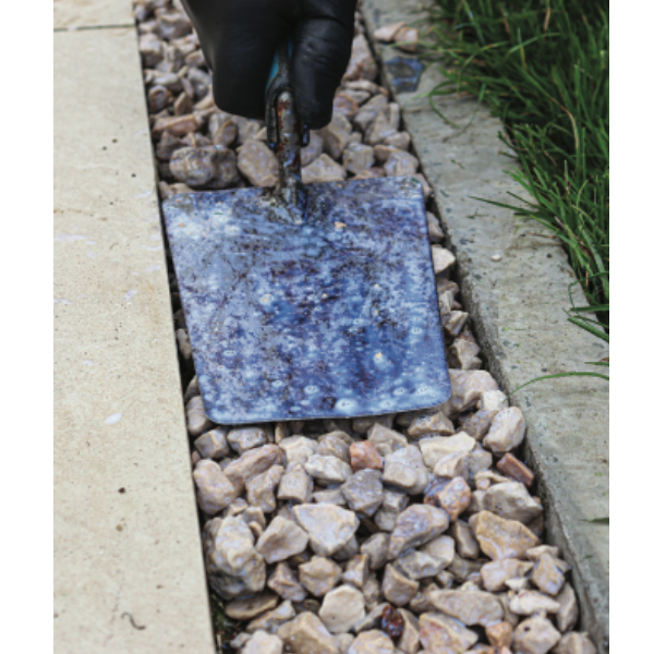 Person placing a blue square tile into a bed of small stones.