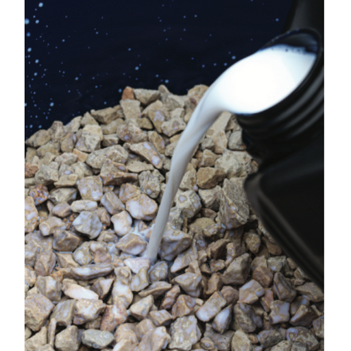 White liquid being poured onto a pile of small stones against a dark background