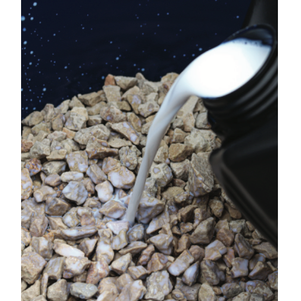 White liquid being poured onto a pile of small stones against a dark background