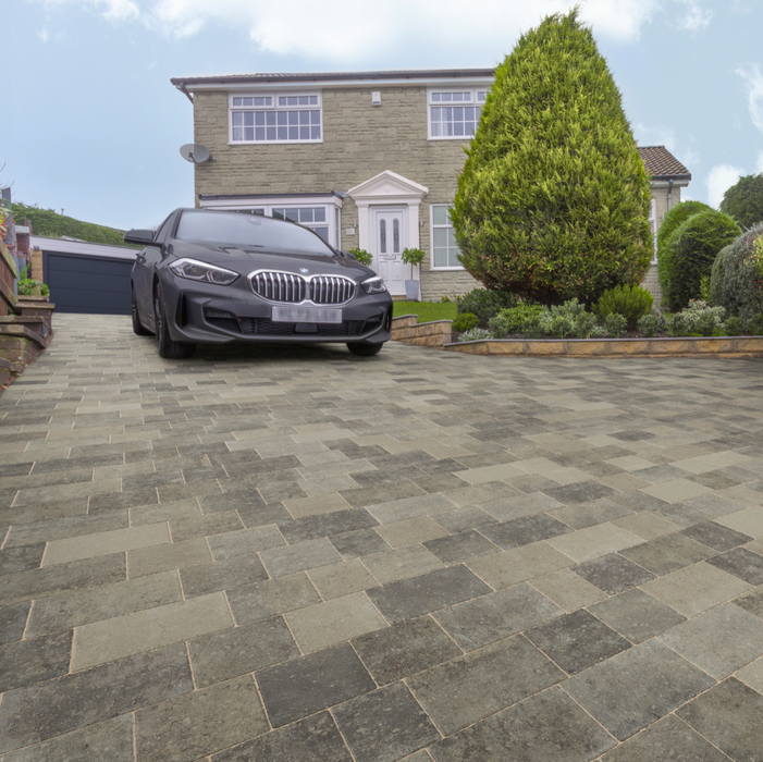 Gray stone driveway with a black car parked in front of a house