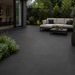 Anthracite porcelain patio with 900x600 slabs laid in a contemporary garden with outdoor seating and dark landscaped borders.