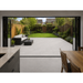 View from inside a UK home looking out onto a Kandla Grey porcelain patio with 900x600 slabs and garden lawn. 