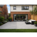 Kandla Grey porcelain patio with 900x600 slabs laid outside a modern UK house with lawn and garden planting.