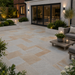 Kandla Grey Indian sandstone patio laid outside a rendered English home with garden lighting, raised planters and outdoor seating.