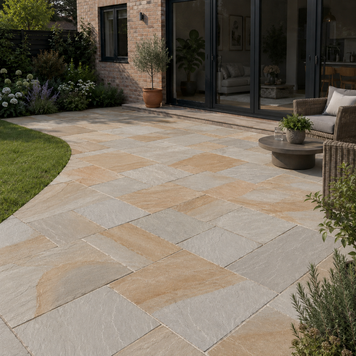 Kandla Grey Indian sandstone patio laid at a modern English brick home with mixed-size natural stone paving, bifold doors and garden seating.