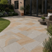 Kandla Grey Indian sandstone patio laid at a modern English brick home with mixed-size natural stone paving, bifold doors and garden seating.