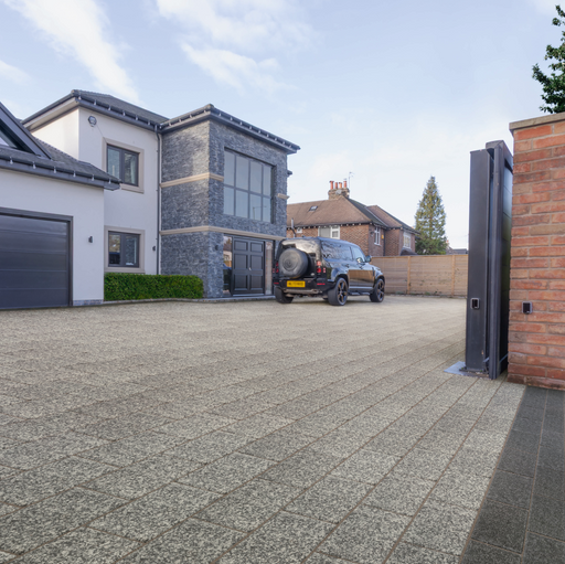 Modern house with a driveway and car, featuring a gate and surrounding landscape.