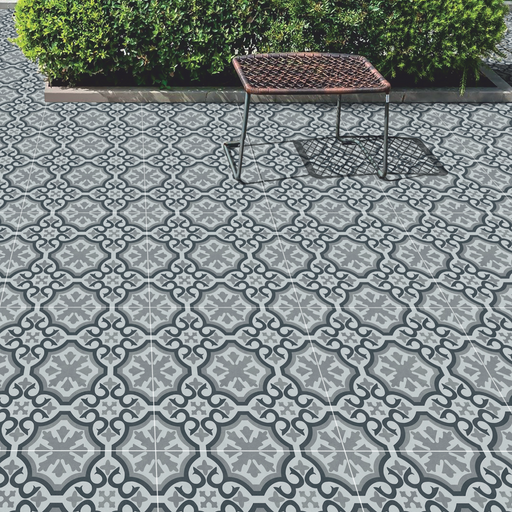 Grey patterned porcelain paving installed in a garden seating area with a woven bench.