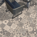 Patterned porcelain paving with mixed grey decorative designs beneath contemporary outdoor seating. 