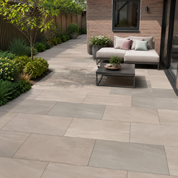 Raj Green porcelain patio with outdoor seating beside a modern brick house and landscaped garden borders.