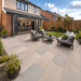 Raj Green porcelain patio laid outside a modern UK new build house with garden lawn, fencing and outdoor seating.