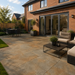 Rustic Copper porcelain paving laid at the rear of a modern English brick house with patio furniture and lawn.