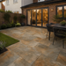 Rustic Copper porcelain paving installed in a rear garden patio at an English style house with dining area and warm evening lighting.