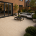 Sand porcelain paving laid in a contemporary UK garden with outdoor sofa, coffee table and planted borders.