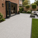 Silver Granite porcelain paving laid at the rear of a modern English brick house with bifold doors, garden furniture and lawn edge.