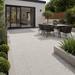 Silver Granite porcelain paving installed at a modern rendered rear extension with black aluminium doors, outdoor dining set and raised planters.