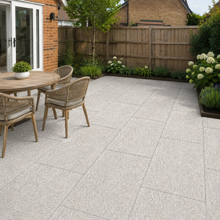 Silver Granite porcelain paving laid in a traditional English rear garden with dining table, timber fencing and planted borders.